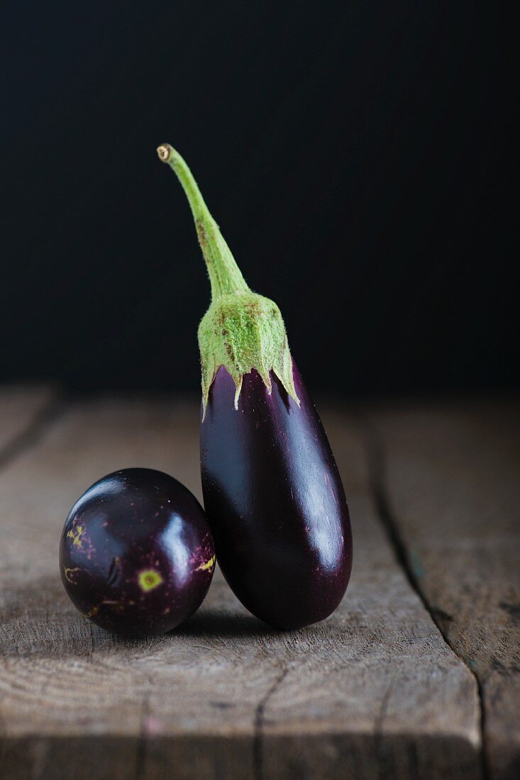 Two baby aubergines on a wooden tabletop