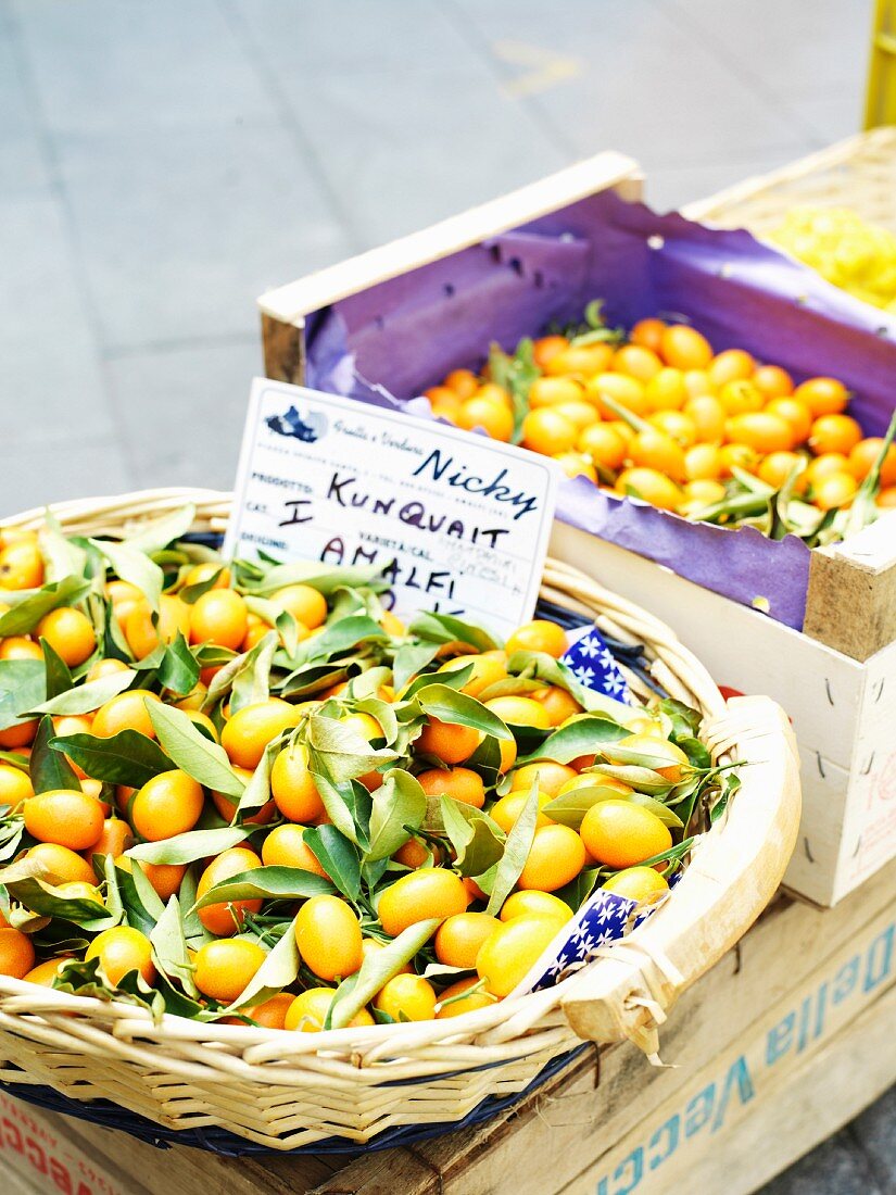 Kumquats in a crate and in a basket at a market in Italy