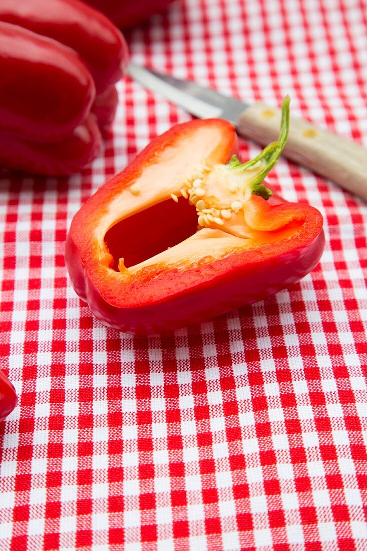 Red peppers on a checked tablecloth with a knife