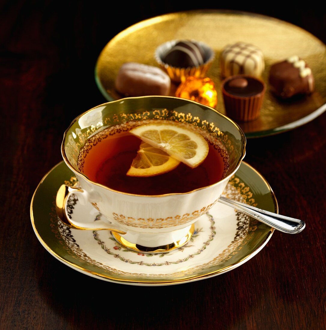 A cup of Earl Grey tea with lemon, by a plate of chocolates