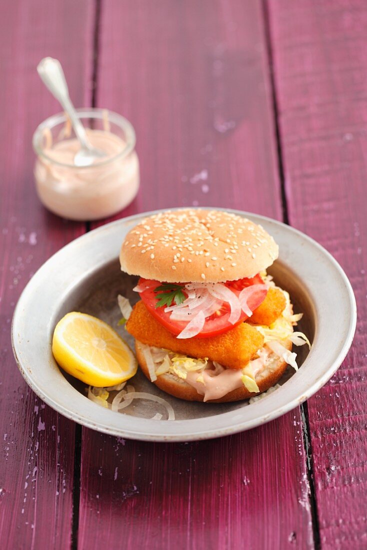 Fish fingers in a burger bun with onions and tomato