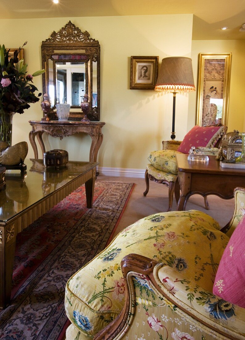 Yellow, Baroque-style living room with ornate wall mirror and gilt coffee table with glass top