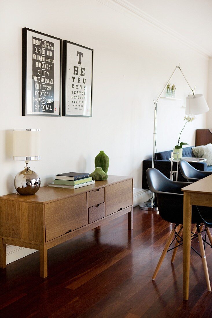 Open-plan interior with retro sideboard and black Eames chairs at dining table