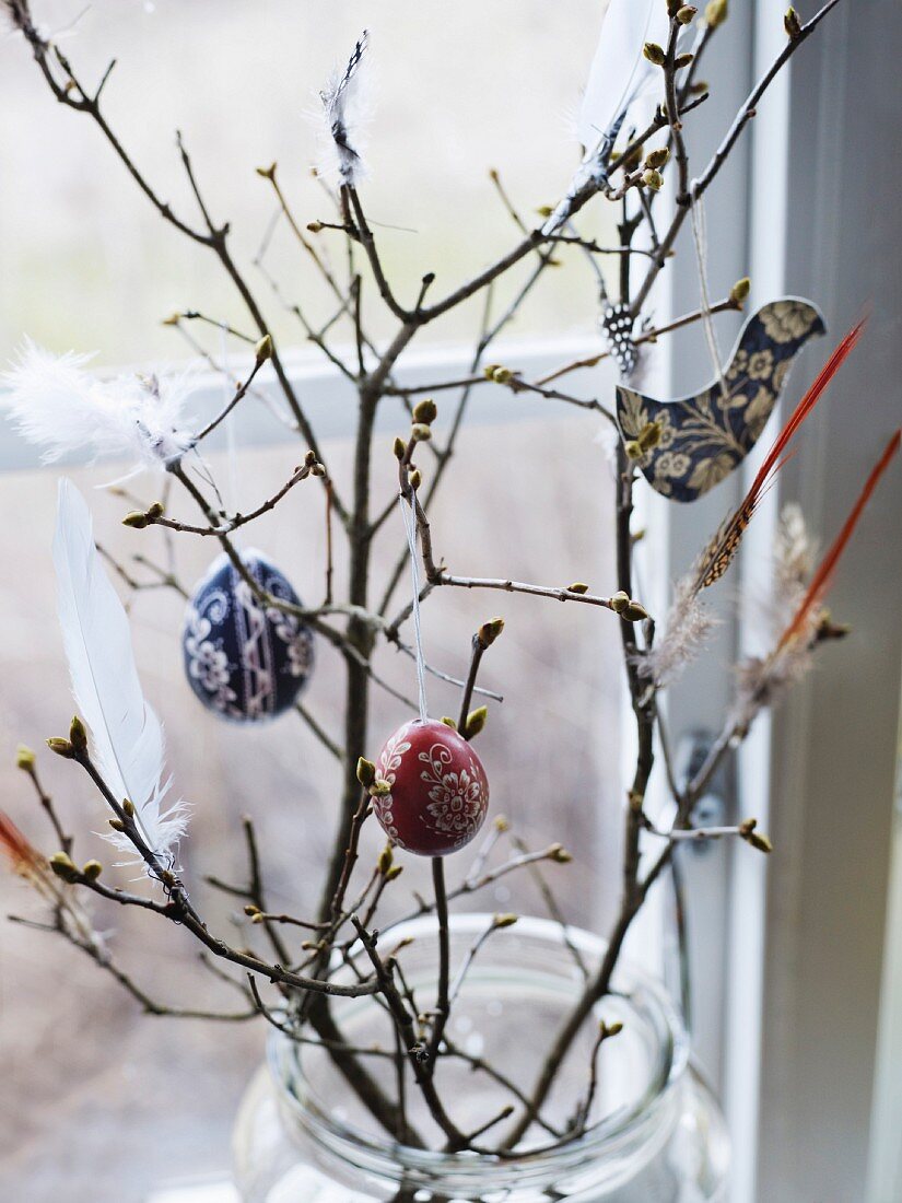 Feather and decorations hanging on bare branches