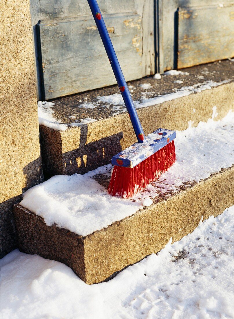 A broom on stairs covered in snow.