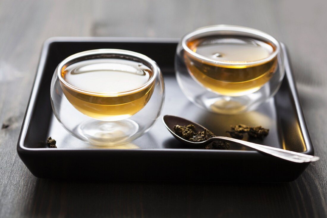 Aufgebrühter grüner Tee in Glasschälchen