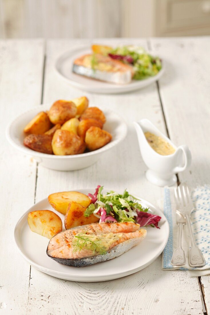 Barbecued salmon steak with bearnaise sauce, potatoes and salad leaves