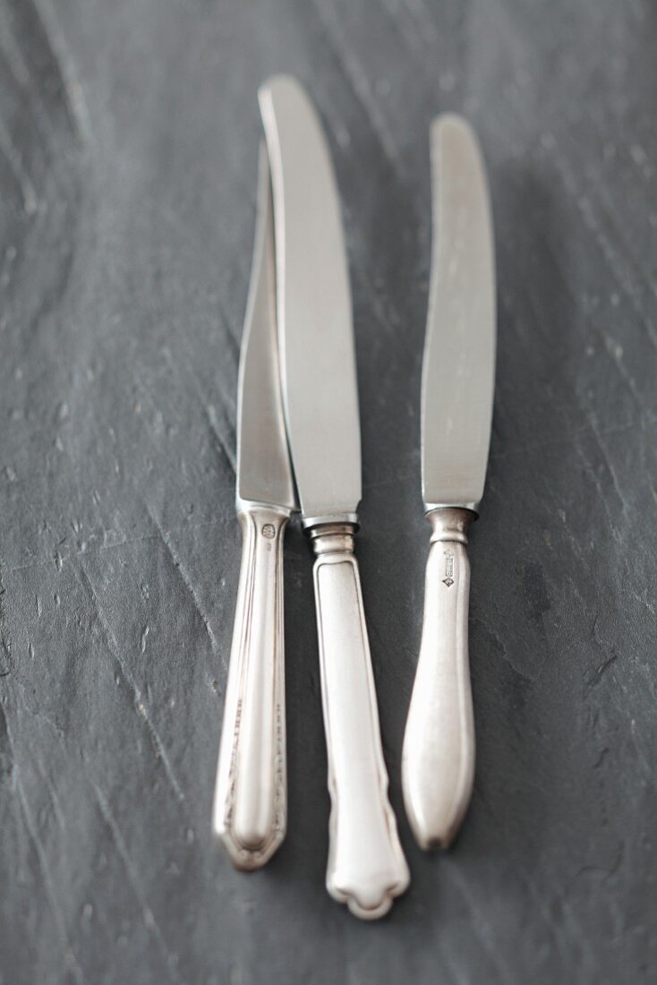 Three knives on a slate surface