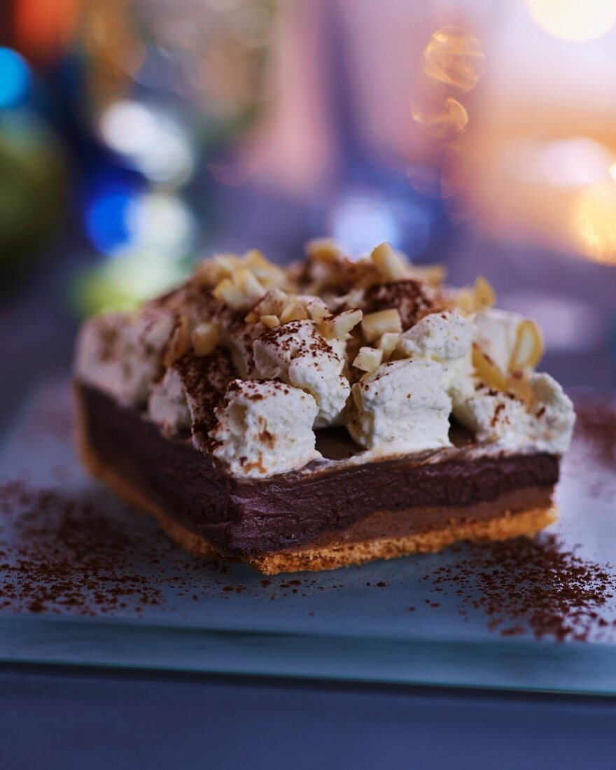 A serving of chocolate & caramel cake topped with nuts