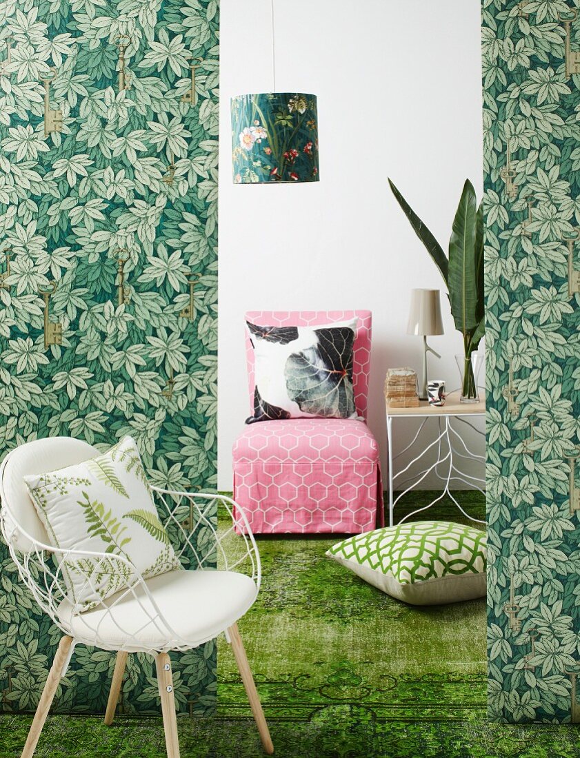 Bolts of fabric in jungle pattern as partition in front of loose-covered easy chair and side table on green carpet
