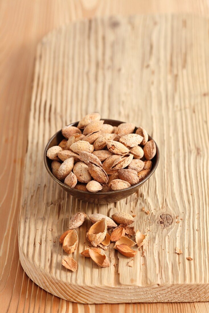 Almonds in a small bowl on a chopping board
