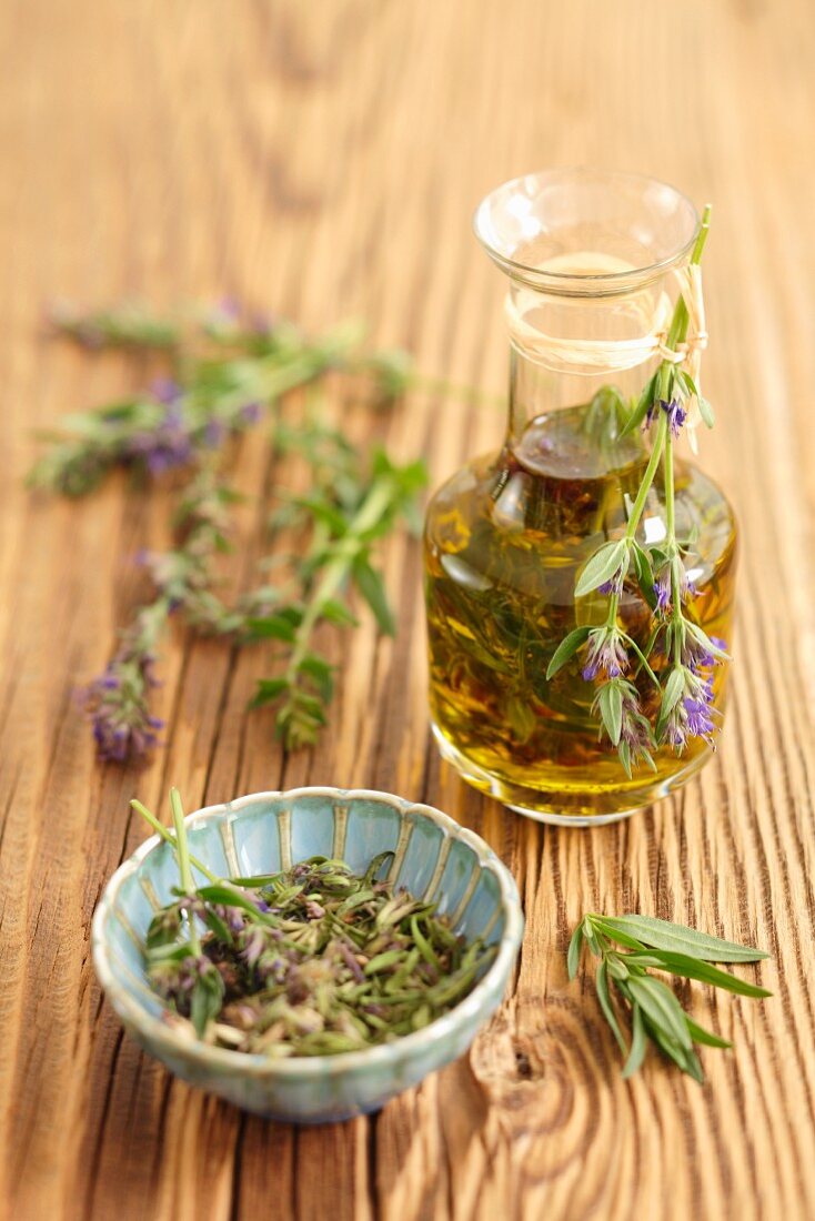 Olive oil with hyssop, and fresh hyssop on a wooden surface