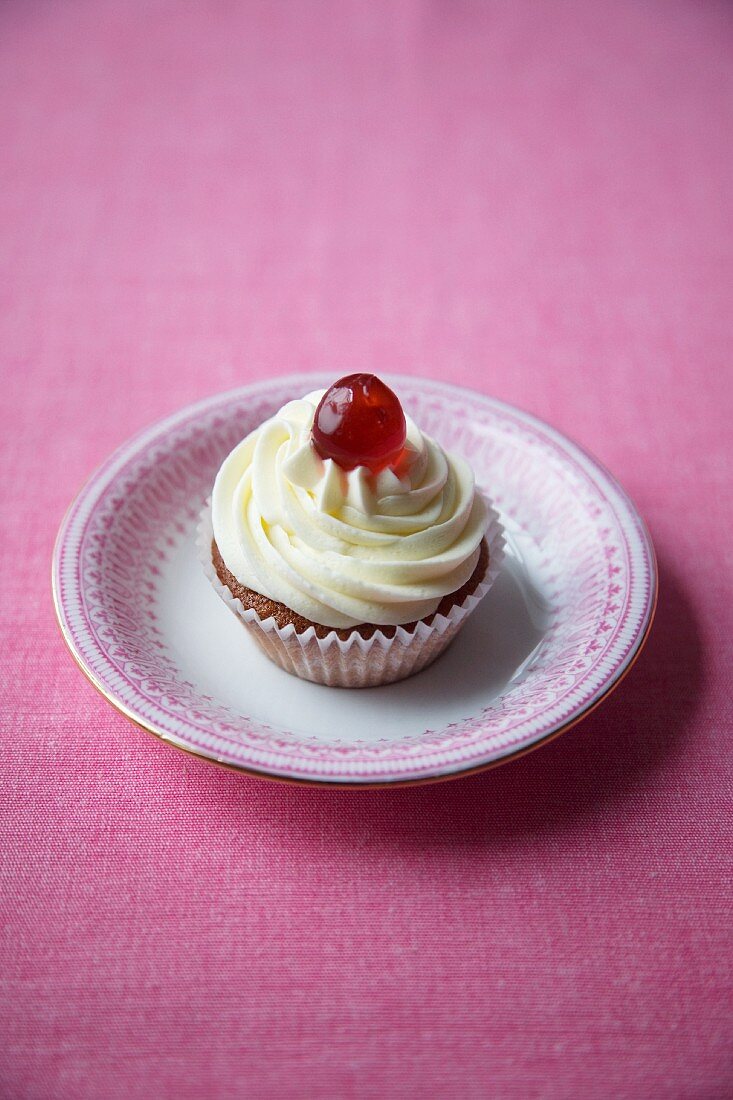 Cherry cupcake with cream icing and a glacé cherry