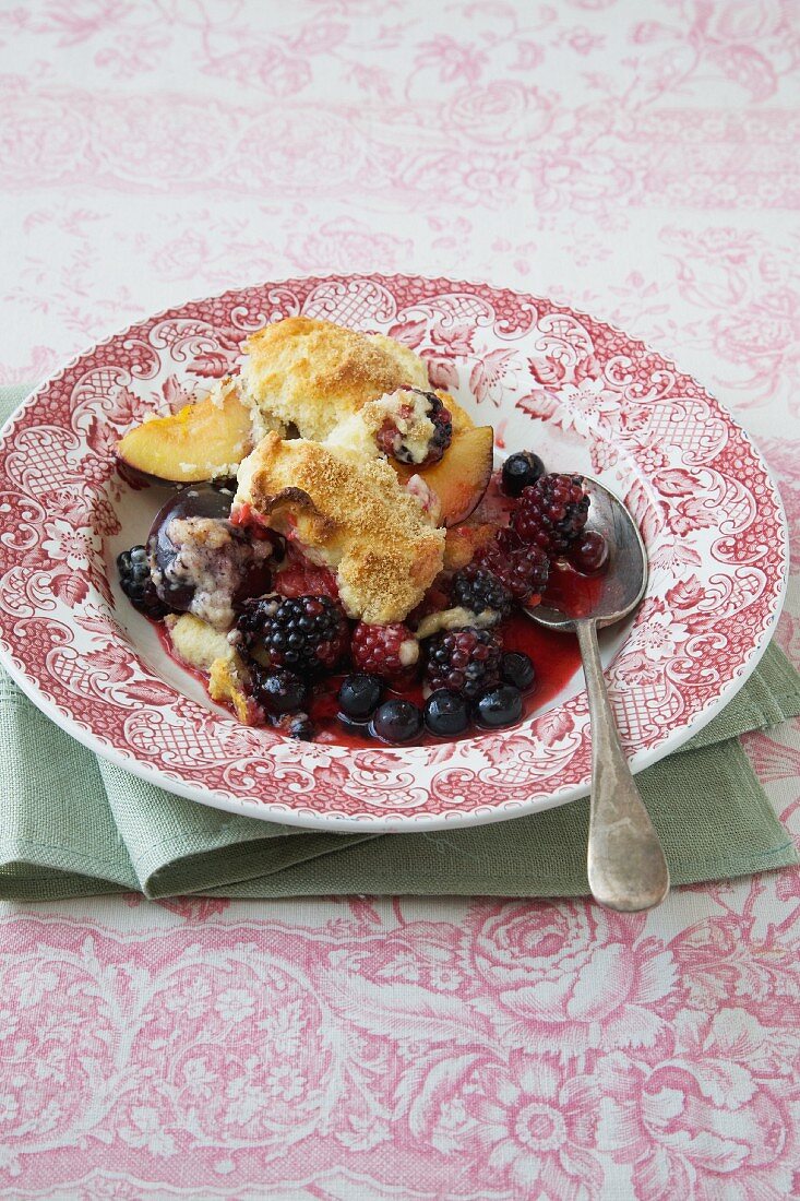 Eine Portion Beeren-Pflaumen-Cobbler auf Teller