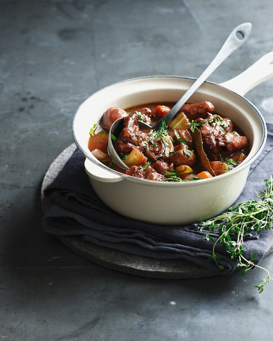 Beef bourguignon in pan with ladle