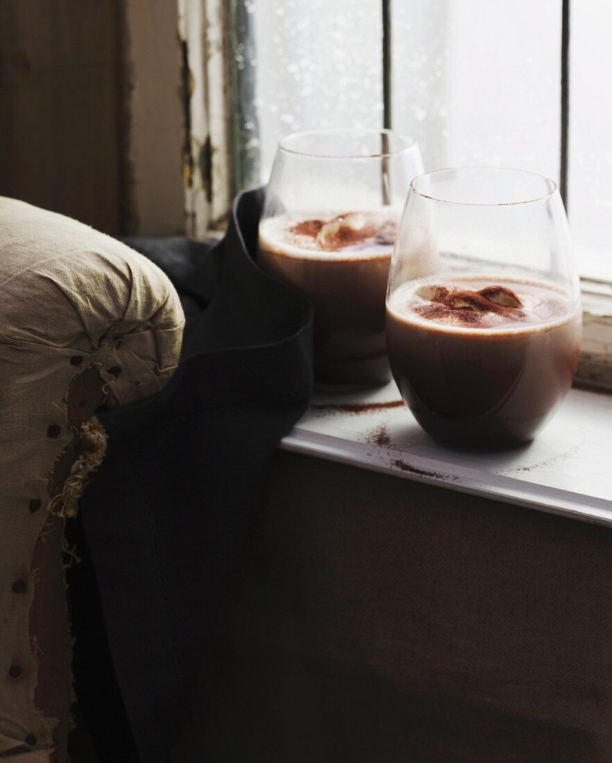 Two glasses of hot chocolate on windowsill
