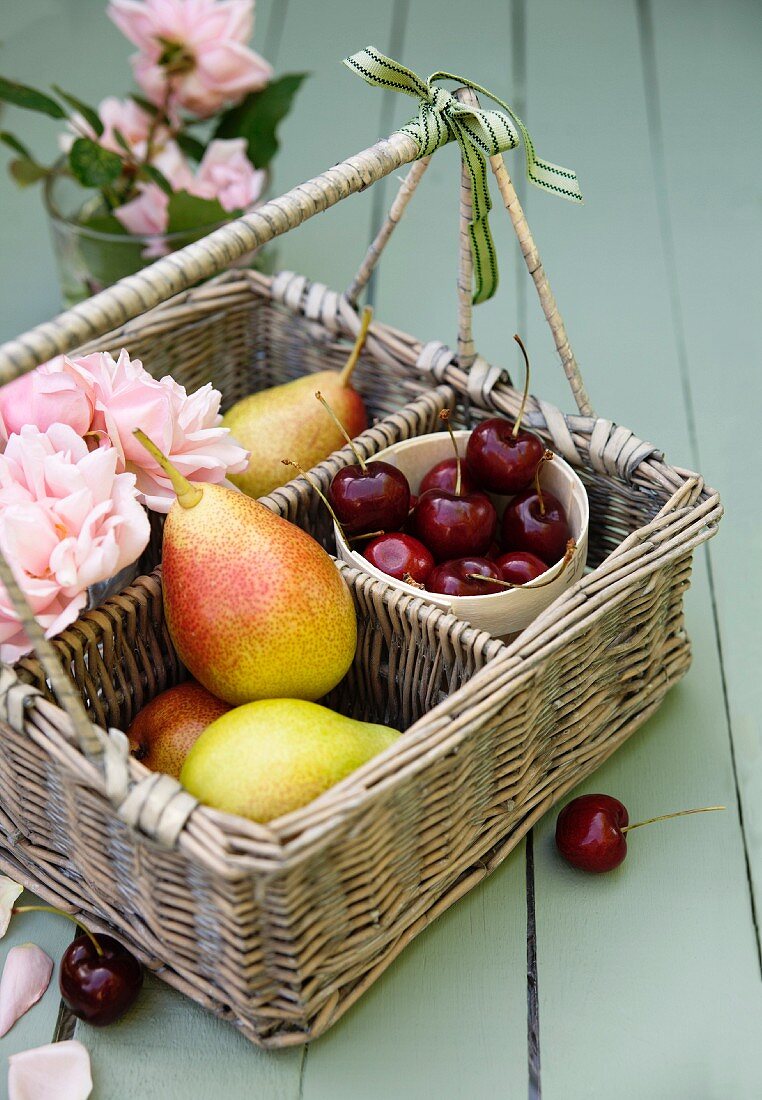 A basket of fresh pears, cherries and roses