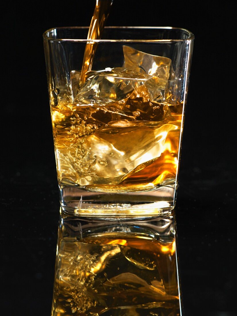 Scotch wird in ein Glas mit Eis gegossen