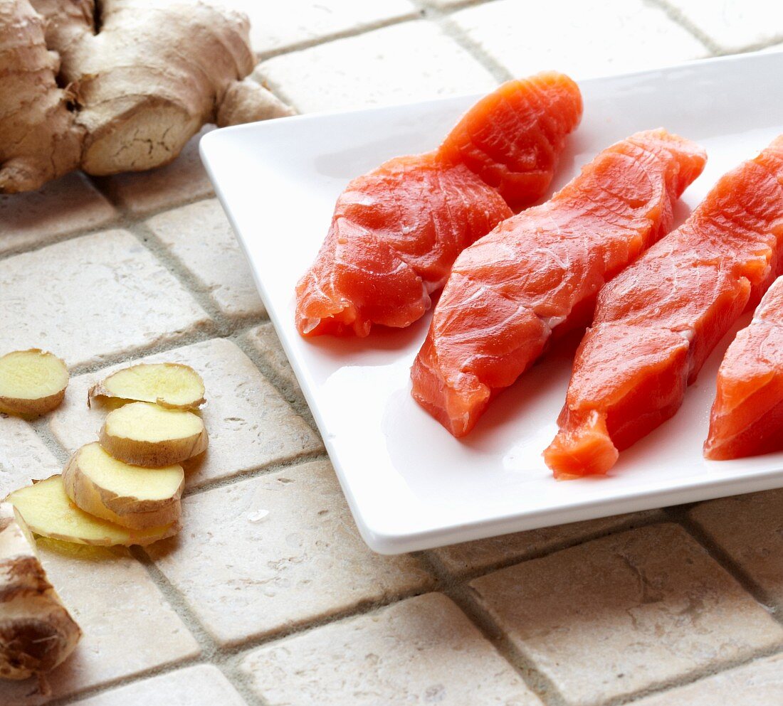 Fresh Pieces of Raw Salmon Steak on a White Plate and Fresh Ginger