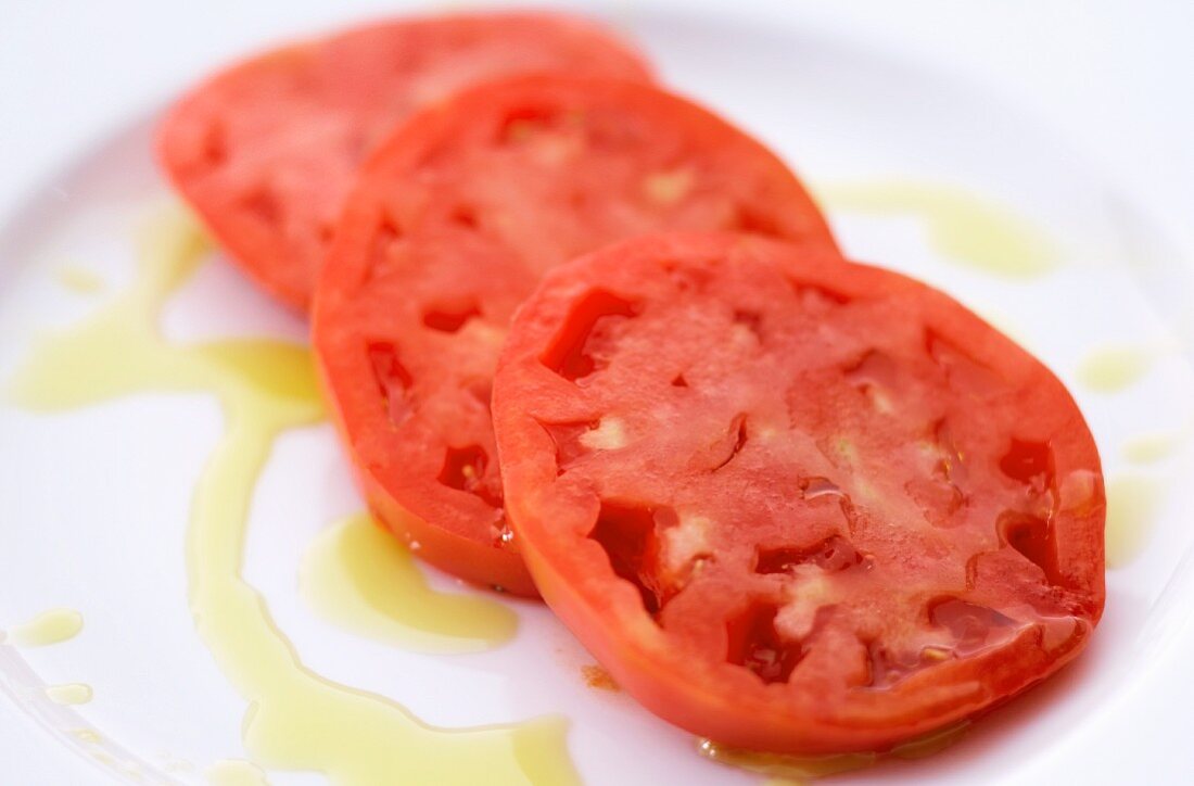 Sliced Tomatoes on a White Plate Drizzled with Olive Oil