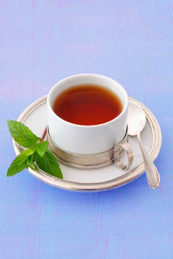 A cup of peppermint tea with a sprig of mint