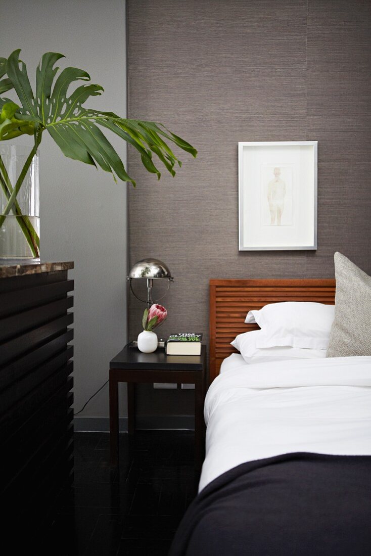 Masculine bedroom with black, angular furniture and grey, structured wallpaper