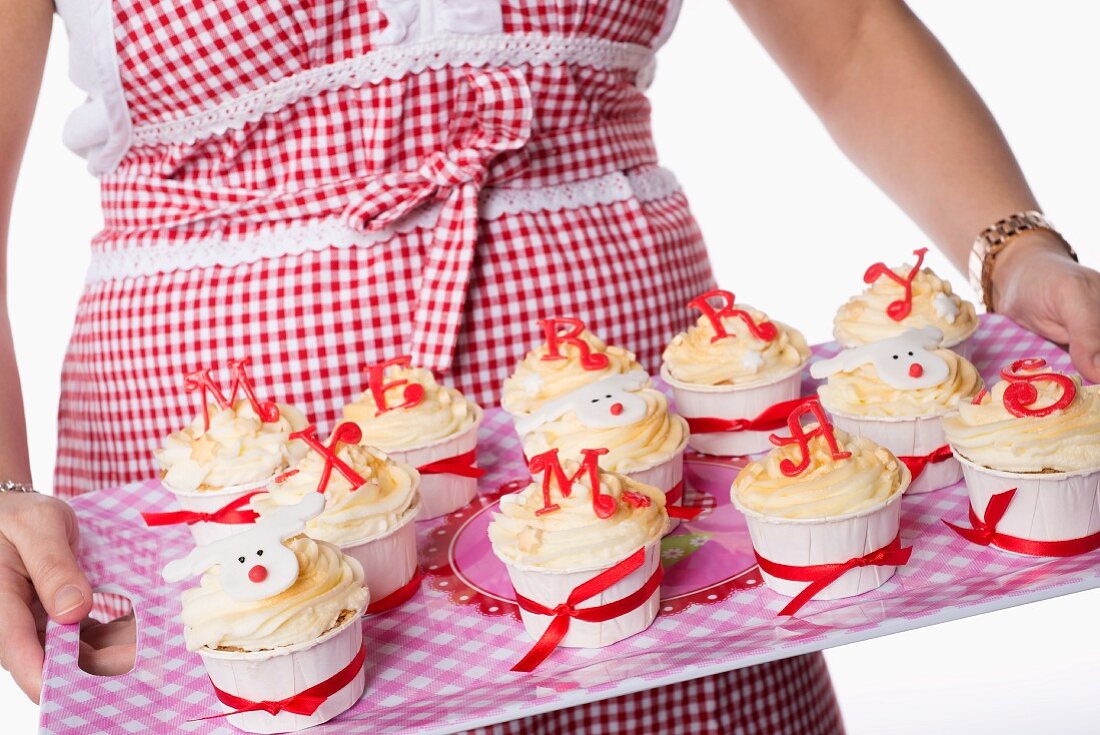 Cupcakes with icing spelling out 'Merry Xmas', on a tray