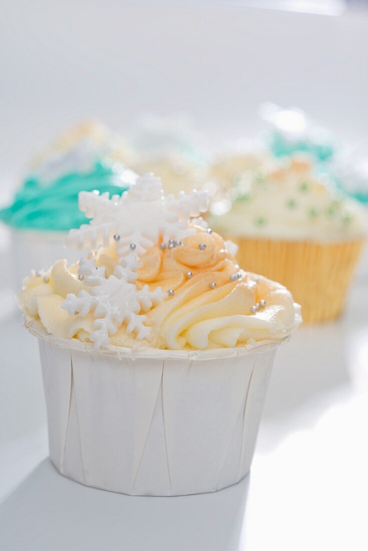 Cupcake mit gelbem Frosting, Silberperlen und Schneeflocken verziert