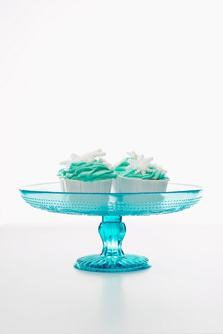 Cupcakes decorated with green icing and snowflakes, on a cake stand