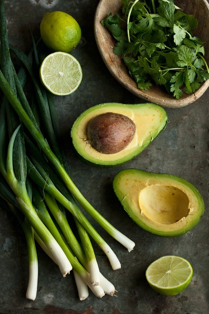 Zutaten für Guacamole: Avocados, Frühlingszwiebeln, Limetten und Koriandergrün