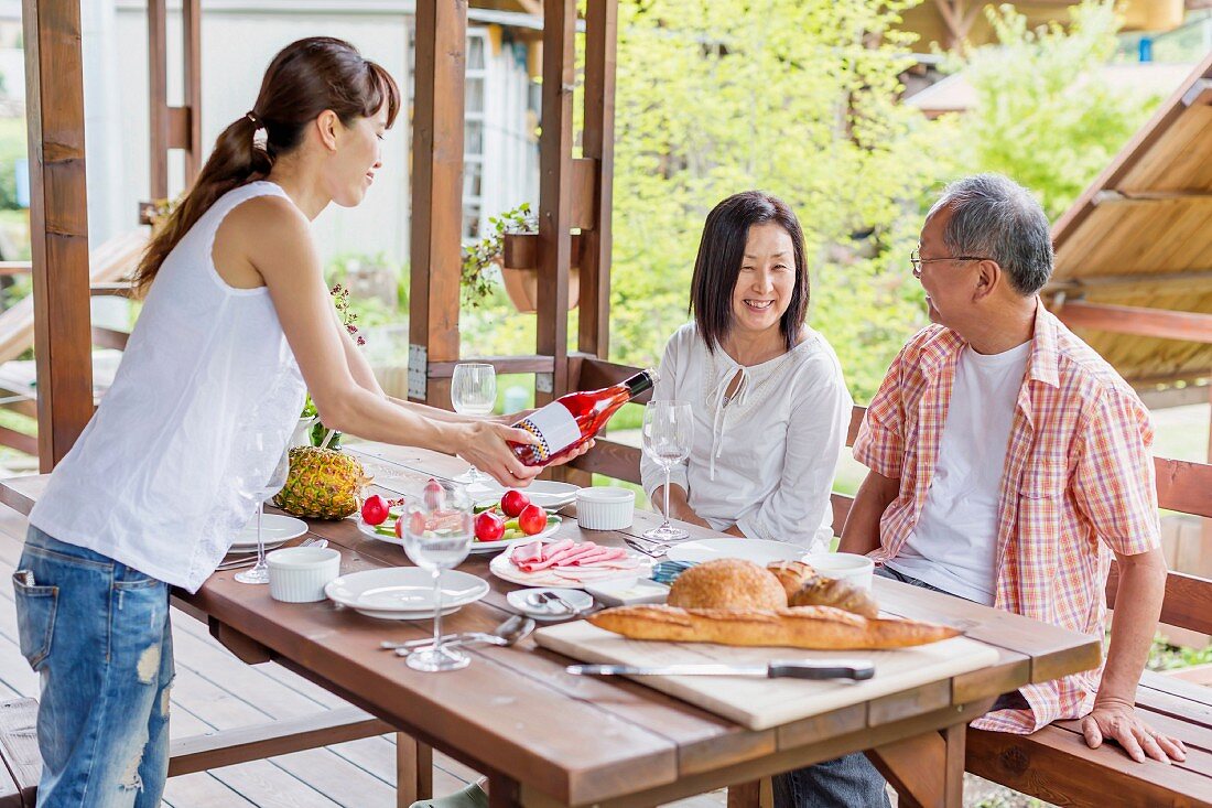 Woman serving wine to parents at dining table