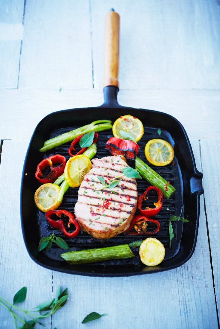Smoked pork chop in a griddle pan with lemons and peppers