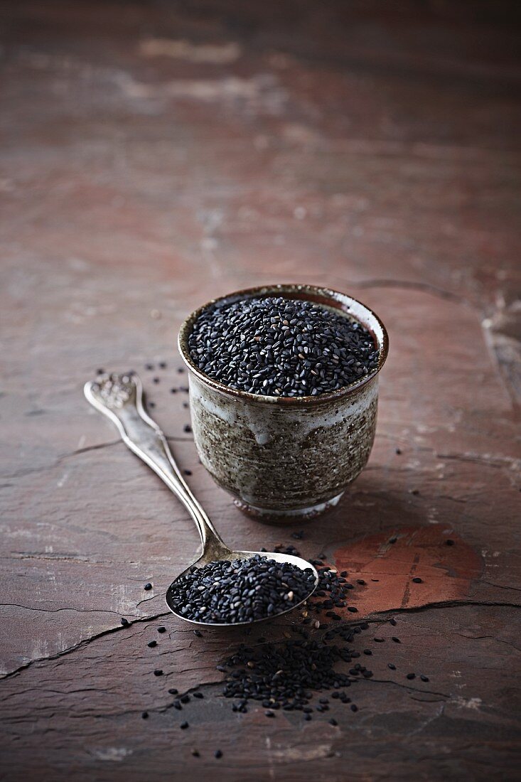 Black sesame seeds on a spoon and in a pot