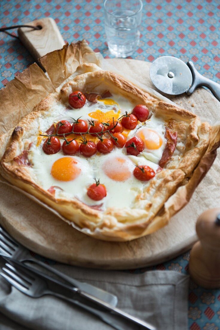 Puff pastry pizza with fried eggs and tomatoes, for breakfast