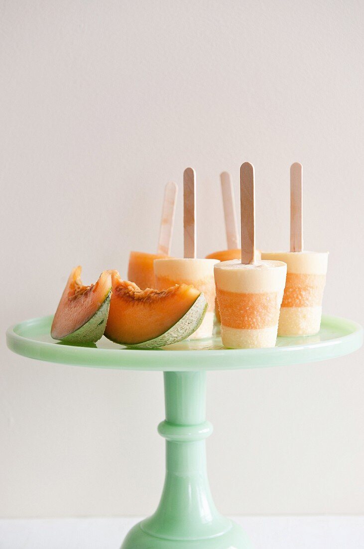 Melon ice lollies and fresh melon wedges on a cake stand