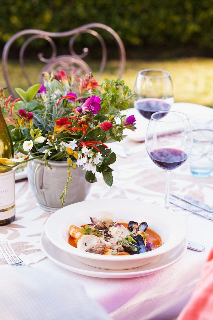 Fröhlicher Blumenstrauss und Meeresfrüchtesuppe auf gedecktem Tisch