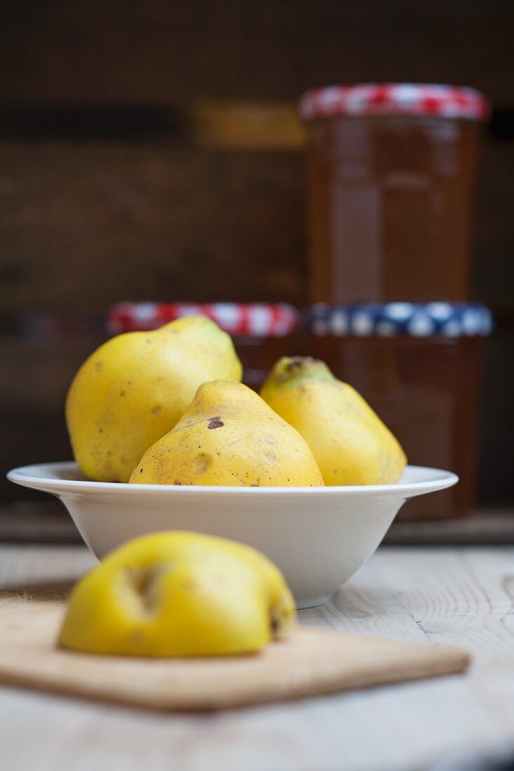 Fresh quinces in front of jam jars filled with quince jelly