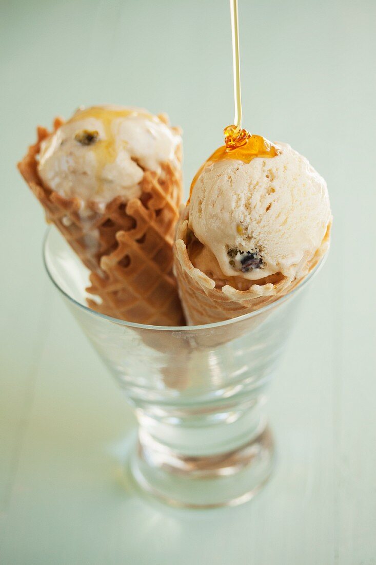 Ice cream in wafer cones, being drizzled with honey