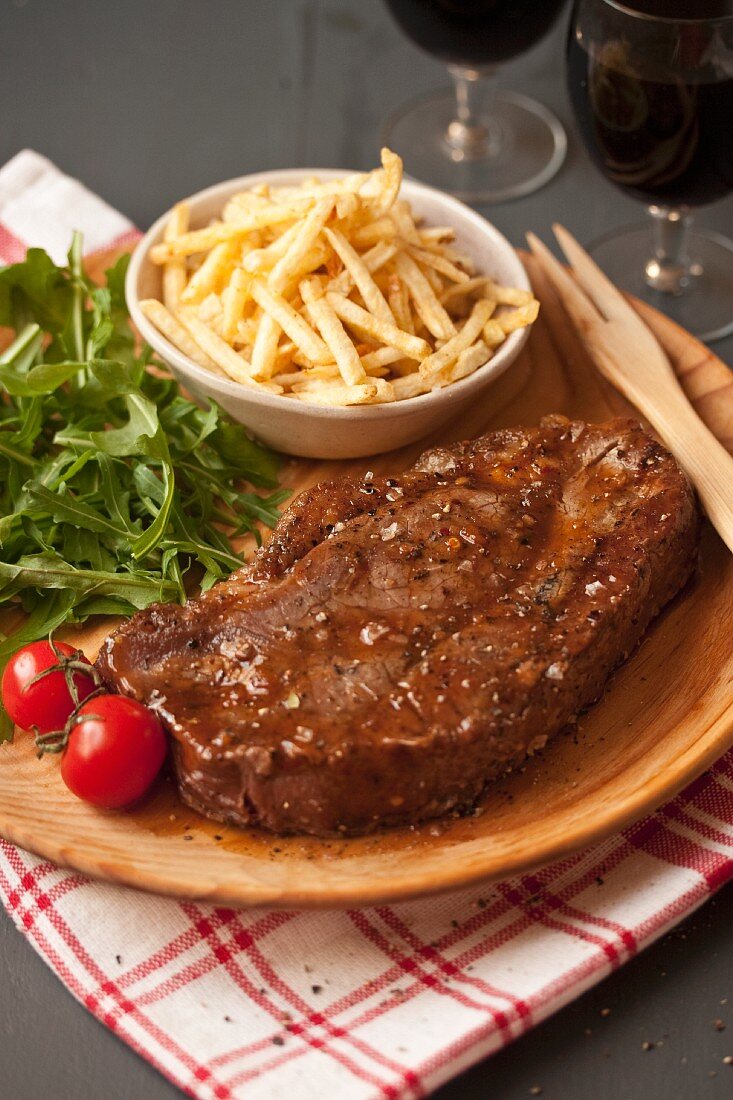Beef steak with skinny fries, rocket and tomatoes