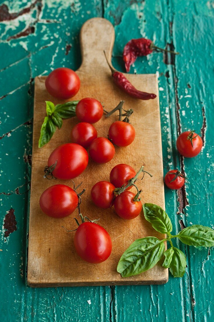 Tomatoes, basil and dried chillies on a chopping board