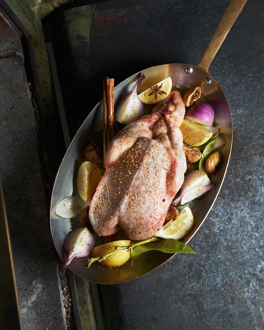 Raw duck with spices and onions in a roasting tin