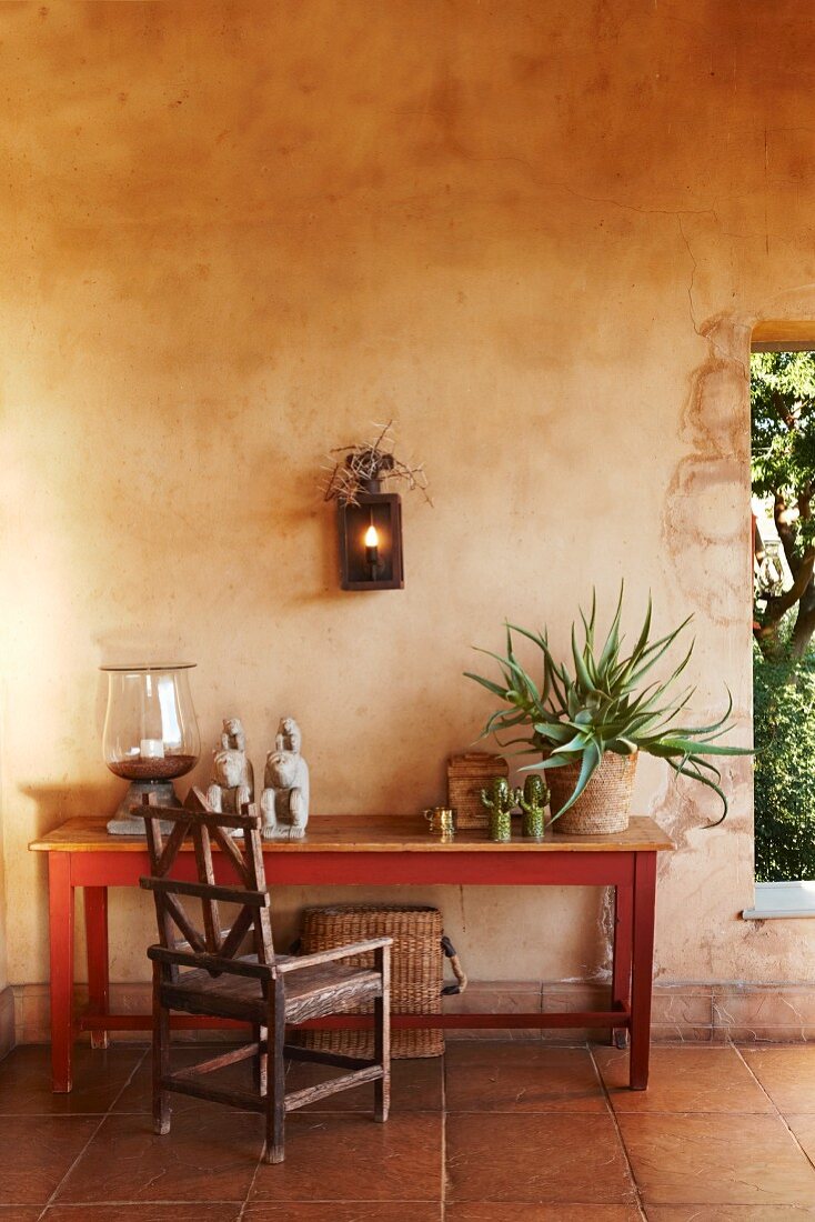 Rustic wooden chair and simple table against wall next to window-style aperture in rustic loggia