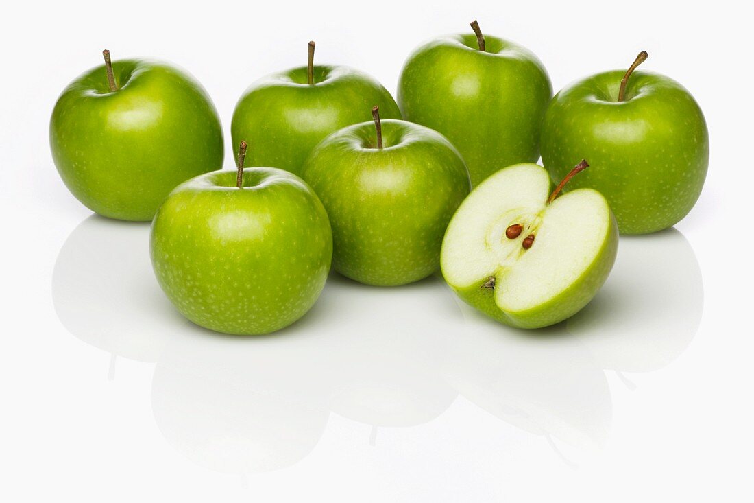 Several Granny Smith apples, whole and cut in half