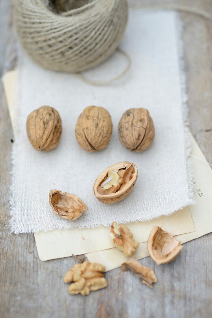 Walnuts, whole and cracked, on a piece of cloth with a roll of twine
