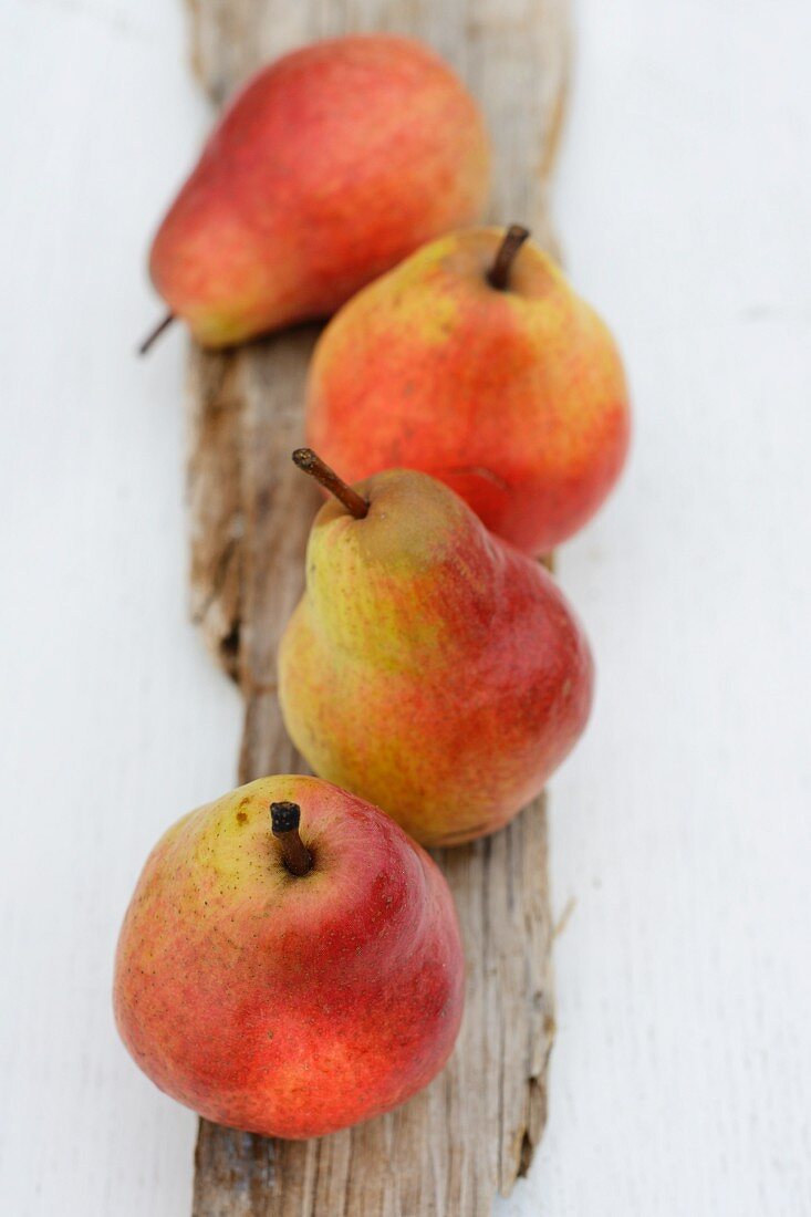 Four red pears on a piece of wood