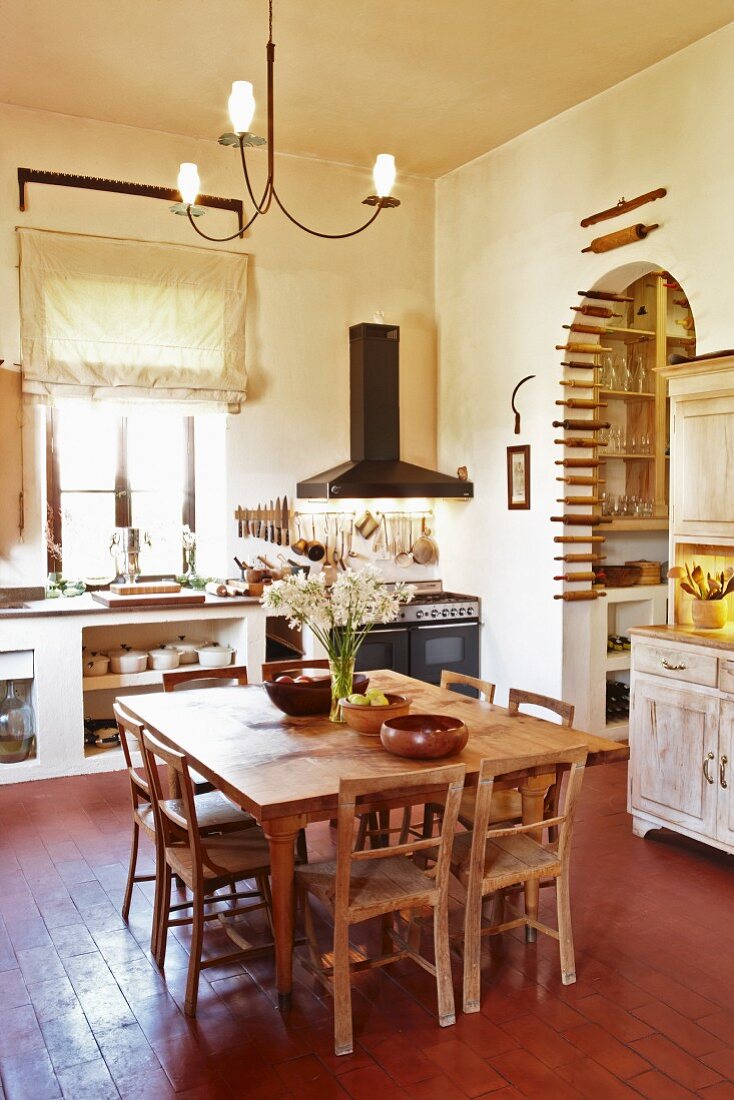 Rustic dining area in spacious kitchen-dining room; collection of rolling pins in arched doorway