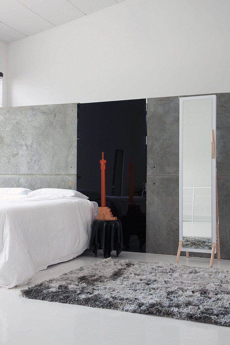 Minimalistisches Galerieschlafzimmer mit grauem Flokatiteppich und großem Standspiegel an grauer Trennwand