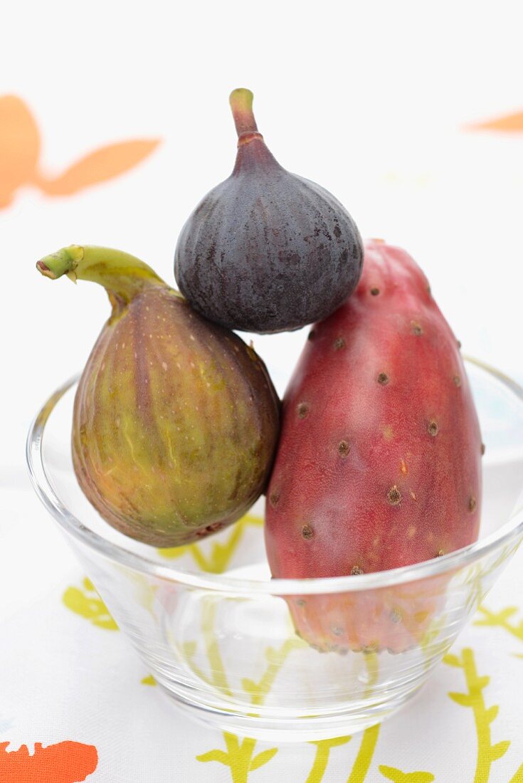 Two figs and a prickly pear in a glass bowl