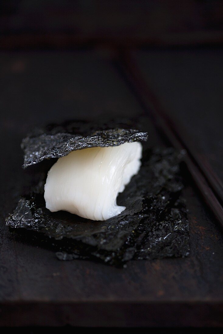 Nigiri-Sushi mit Tintenfisch (Tai) zwischen salzigen Nori (Japan)
