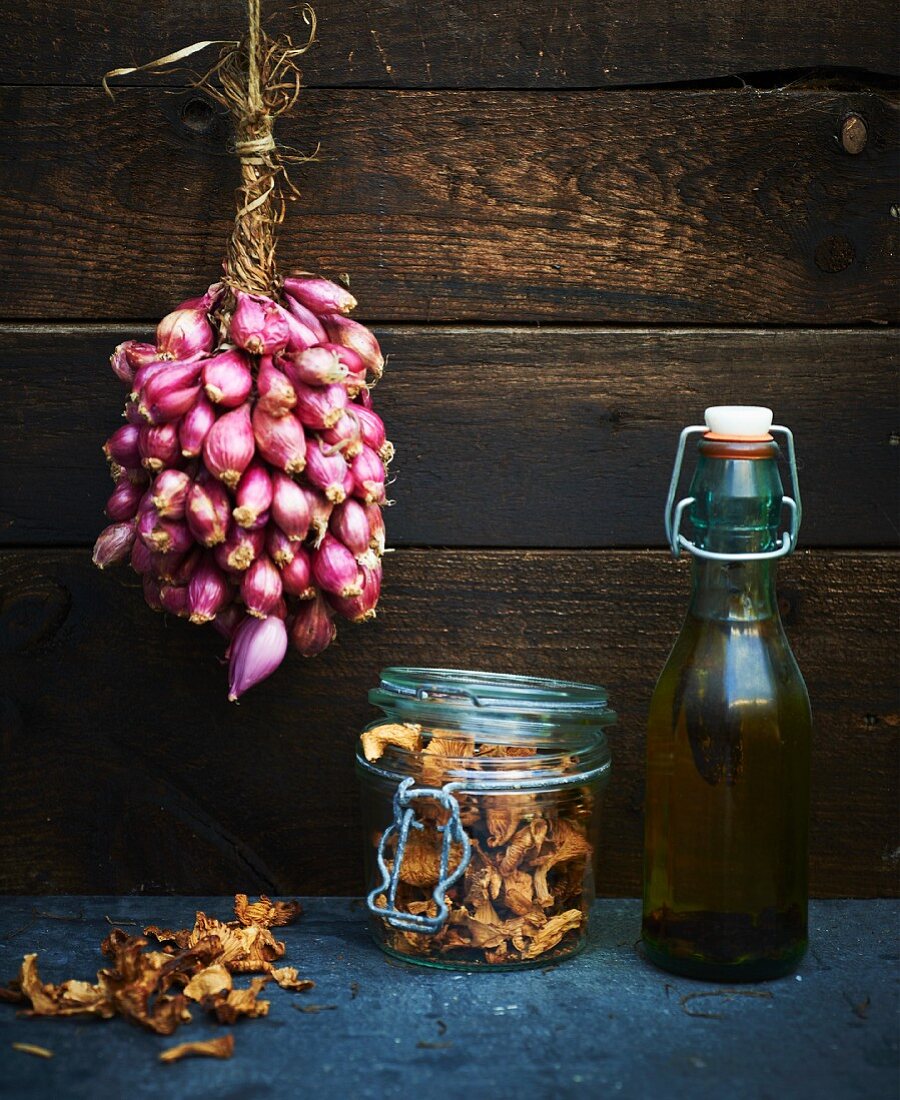 Shallots hanging up, chanterelles in a jar, and a bottle of olive oil